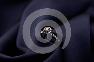 Diamond ring with carat gemstone on a blue silk background