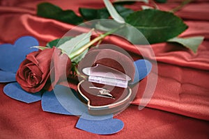 Diamond ring and rose on bright red background