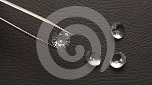 Diamond in tweezer at jeweller hand close up