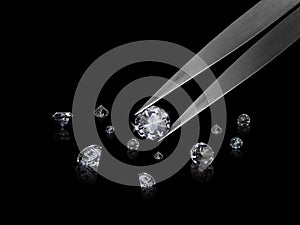 Diamond in tweezers on a black background with diamonds group soft focusing