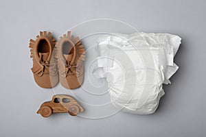 Diaper and baby accessories on grey background, flat lay photo