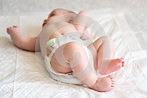 Diapered infant laying with feet in focus. Concept of cherishing small moments in life