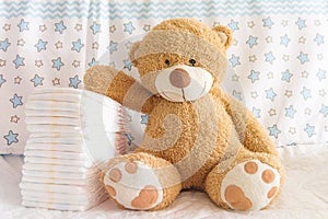 Diapers with baby soft clothes for newborns bear on the background of the nursery and crib