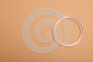 Diaphragm vaginal contraceptive ring on beige background, top view. Space for text