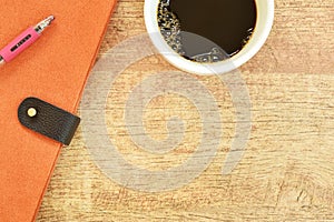 Diary book and pen with black coffee cup on wooden table photo