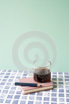 Diary notebook, pencil, coffee on blue tile desk. mint wall background. workspace