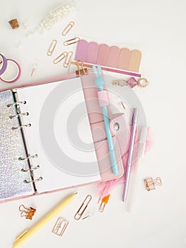 Diary opens with white and holographic page. Pink planner with cute stationery photographing in flatlay style. Top view of pink