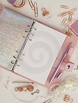 Diary opens with white and holographic page. Pink planner with cute stationery photographing in flatlay style. Top view of pink