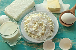 Diary products - milk, cottage cheese, butter and eggs - on a wooden surface