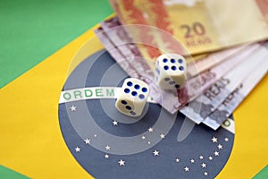 Dice cubes with brazilian money bills on flag of Brasil Republic. Concept of luck and gambling in Brasil
