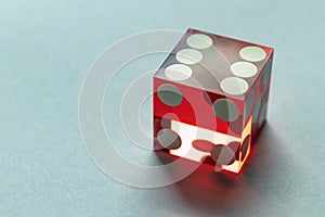 Dice Deluxe perfect red close-up with copy space. Six, with a light shadow, on a gray background.