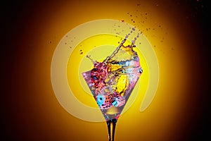 Dice fall in a glass of martini. Colourful cocktail in glass with splash