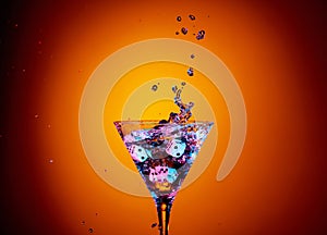 Dice fall in a glass of martini. Colourful cocktail in glass with splash