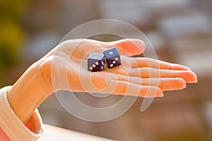 Dice 1 1 in the female hand, sunset background. Gambling devices.