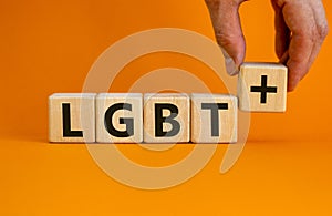 Dice form the acronyms `LGBT+`. Male hand. Beautiful orange background. Concept, copy space