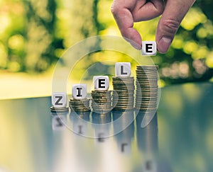 Dice form the German word `Ziele` `goals` in English on increasing high stacks of coins.