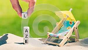 Dice placed next to a beach chair form the word `laze` photo