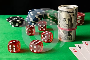 Dice, playing cards, poker chips and twisted 100 dollar bills on