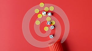 Dice and Yellow Chips Spilling From a Red Cup on a Red Background