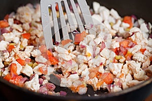 Diced vegetables and meat of a diet turkey in a frying pan Stirring food with a spatula close-up. Roasting poultry meat