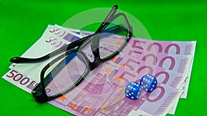 Dices and glasses on top of euro bills