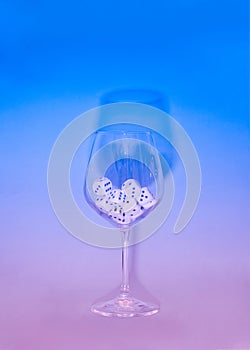 dices in a wine glass on a sky blue and pink neon background.minimal still life abstract design concept