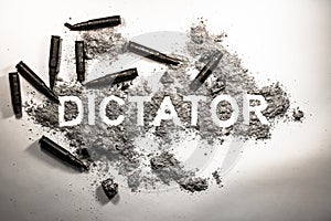 Dictator word written in ash, dirt, dust with bullets around as