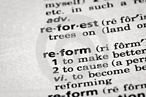 Dictionary definition of the word reform in focus.