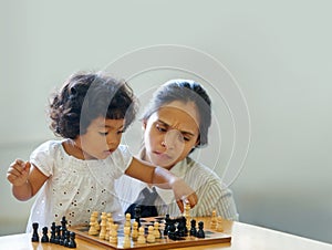 When did she get this smart. A cute little girl playing chess while her mom looks on.