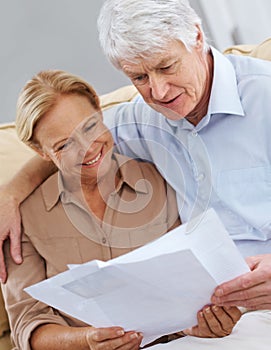 We did good this month. a happy senior couple looking at documents together.