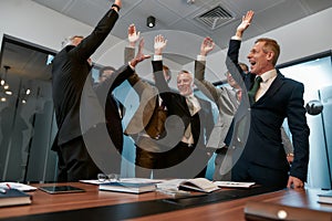We did it. Group of happy business people in formal wear giving each other high-five and smiling while working in the