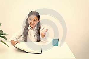 Did you know it. Reading textbook. Girl child reads book while sit table white background. Schoolgirl studying reading