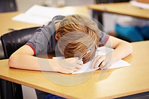 He didnt get enough sleep. A cute little boy asleep at his desk at school.