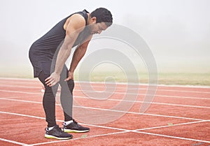 That didnt go according to plan. Full length shot of a handsome young male athlete hunched over on the track after a