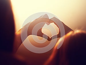 Die-hard groupie. a young woman making a heart sign druing a concert.