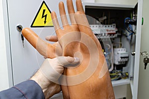 Dielectric gloves in hand holds the employee in front of the electrical panel in the room