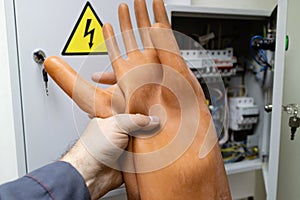 Dielectric gloves in hand holds the employee in front of the electrical panel in the room photo