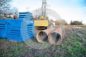 Diesel aggregate and large drill pipes with yellow jib crane for well drilling