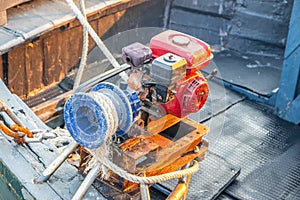 A diesel engine with a rope for raising and lowering a ship`s anchor on the deck of a fishing boat