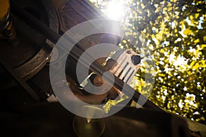 Diesel engine of a walk-behind tractor with a belt drive close-up. Foreshortened view from below with light from the sun
