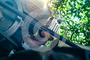 Diesel engine of a walk-behind tractor with a belt drive close-up. Foreshortened view from below with light from the sun