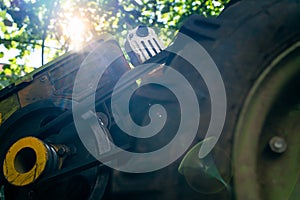 Diesel engine of a walk-behind tractor with a belt drive close-up. Foreshortened view from below with light from the sun