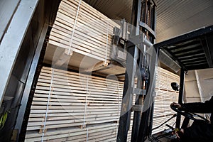 A diesel forklift loads freshly sawn pine logs, girders, bars, beams, bars, boards into a drying chamber. Industrial technology of