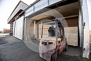 A diesel forklift loads freshly sawn pine logs, girders, bars, beams, bars, boards into a drying chamber. Industrial technology of