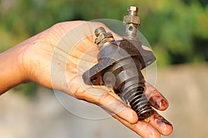 Diesel Fuel injector from an old diesel engine held in hand with a view of its parts