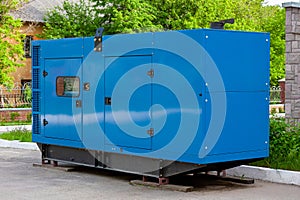 Diesel generator for emergency power supply at the wall of a medical center against the backdrop of green trees in fine weather