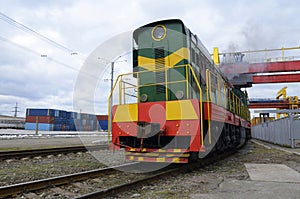 Diesel locomotive pulling freight train loaded with cargo containers at depot of a railway station. Kyiv, Ukraine