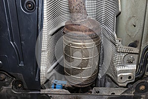 A diesel particulate filter in the exhaust system in a car on a lift in a car workshop, seen from below. photo