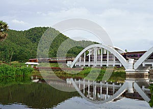 Diesel Train passing the Tha Chom Phu railway bridge or white bridge