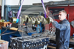 Diesel truck engine repair service. Automobile mechanic installing crankshaft into engine